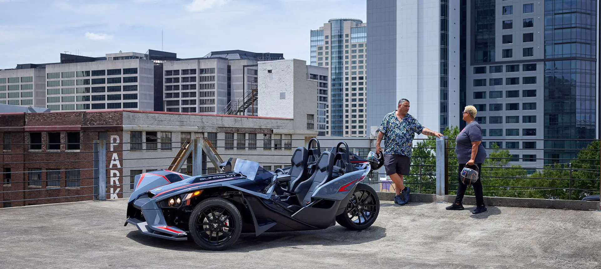 un couple se tenant près d’une moto à trois roues polaris slingshot slr ombrée rouge