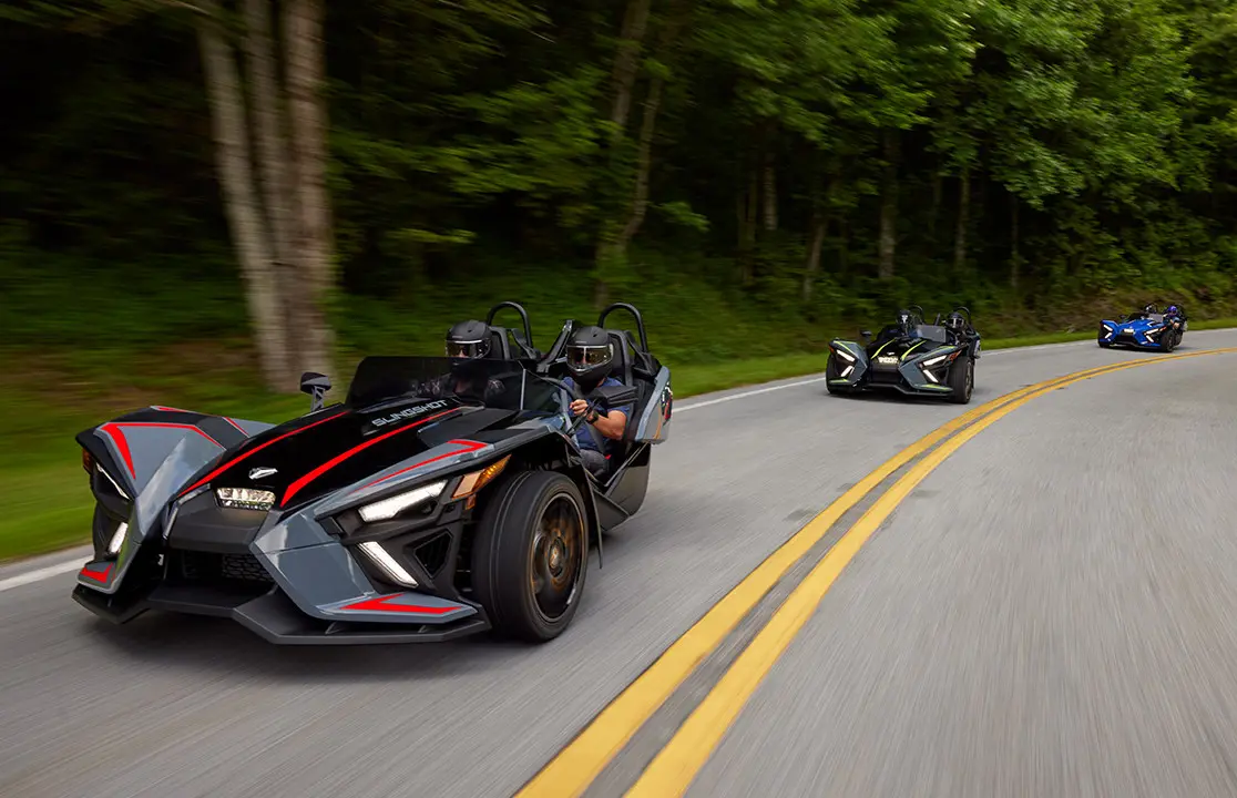 tres motocicletas polaris slingshot slr de tres ruedas que conducen por una carretera