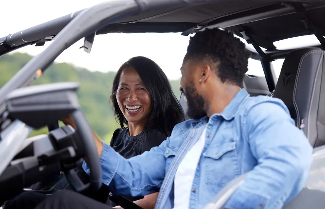 man and woman sitting inside the cockpit of a polaris slingshot roadster