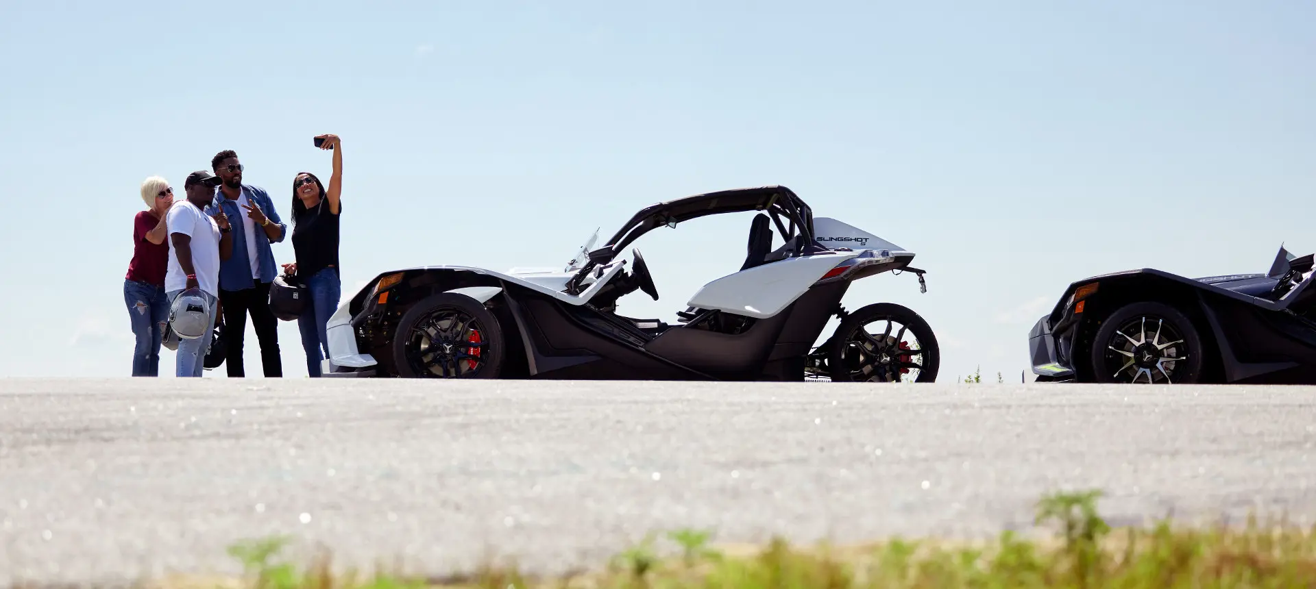 friends taking a selfie in front of hteir polaris slingshot three-wheeled motorcycles