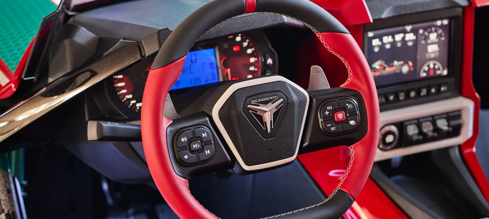 Profil de deux personnes dans un cabriolet Polaris Slingshot 10 2025 circulant sur une grande route.