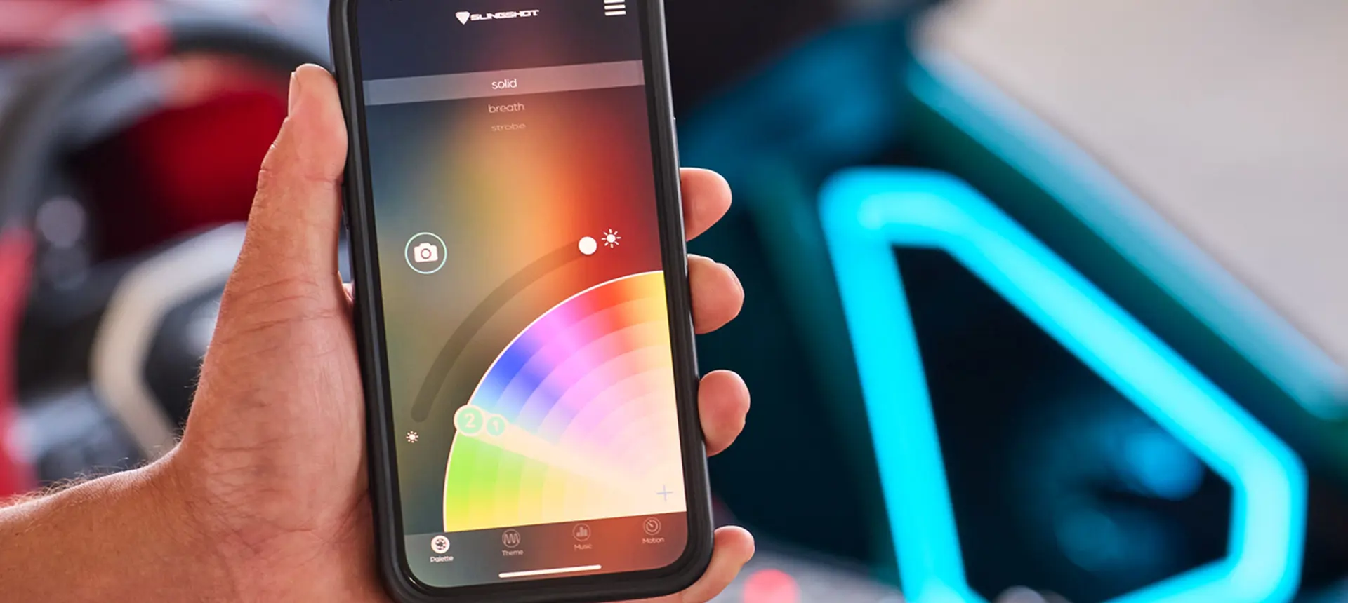 Person holding a cell phone while using an app to adjust the lighting color on their 2025 Polaris Slingshot 10 three-wheeled roadster.