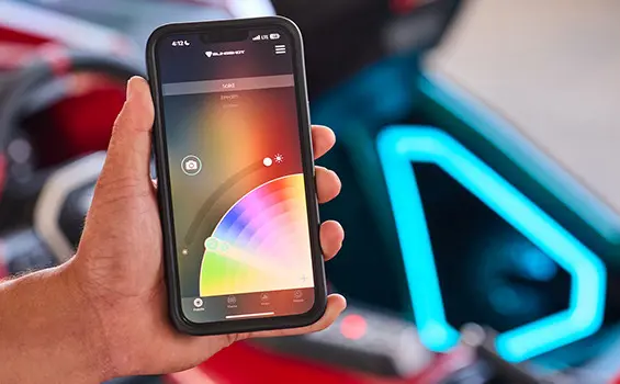 Person holding a cell phone while using an app to adjust the lighting color on their 2025 Polaris Slingshot 10 three-wheeled roadster.