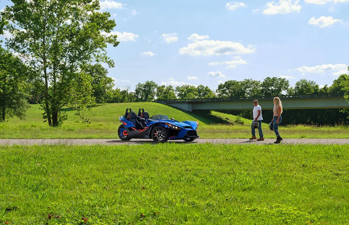 two people walking towards a 2024 slingshot r three-wheeled motorcycle