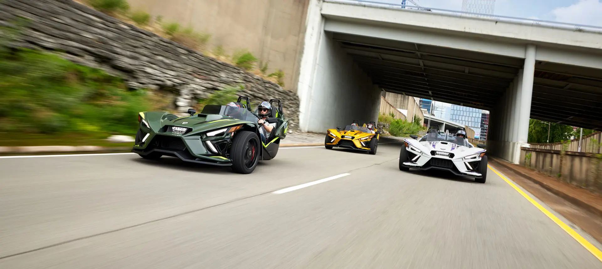 trois motos à trois roues Slingshot r 2024 roulant sur une route