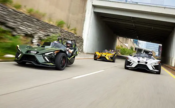 trois motos à trois roues Slingshot r 2024 roulant sur une route