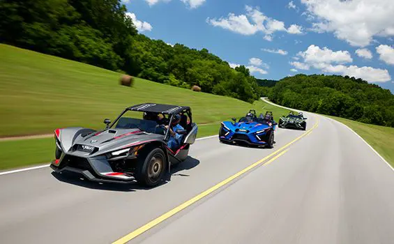 trois motos à trois roues Slingshot r 2024 circulant sur une route de campagne
