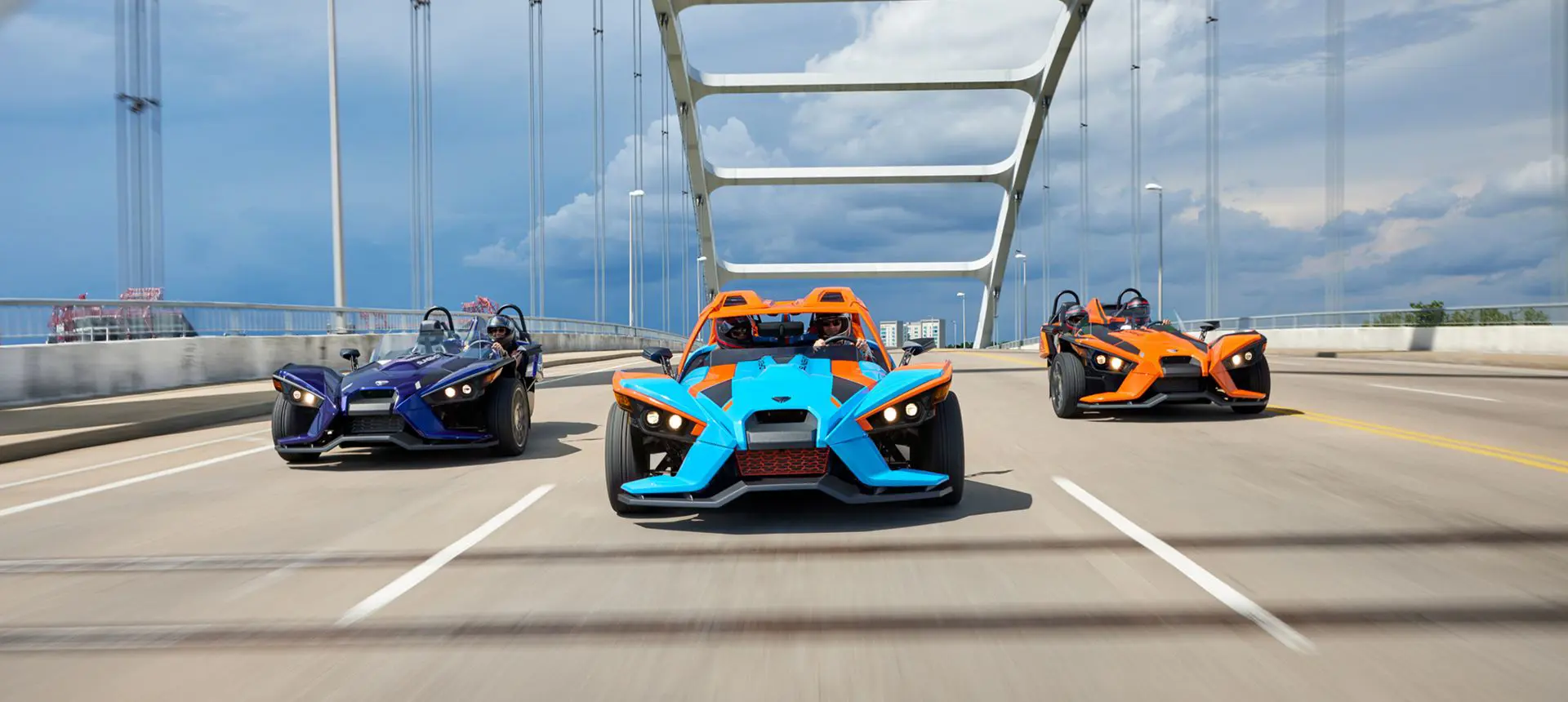 three polaris slingshot SL three-wheeled motorcycles driving on a bridge