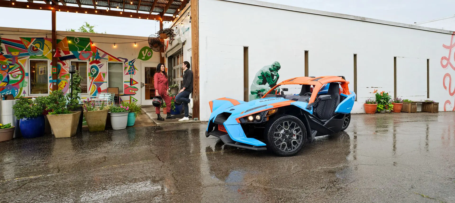 two friends standing near their polaris slingshot sl three-wheeled motorcycle