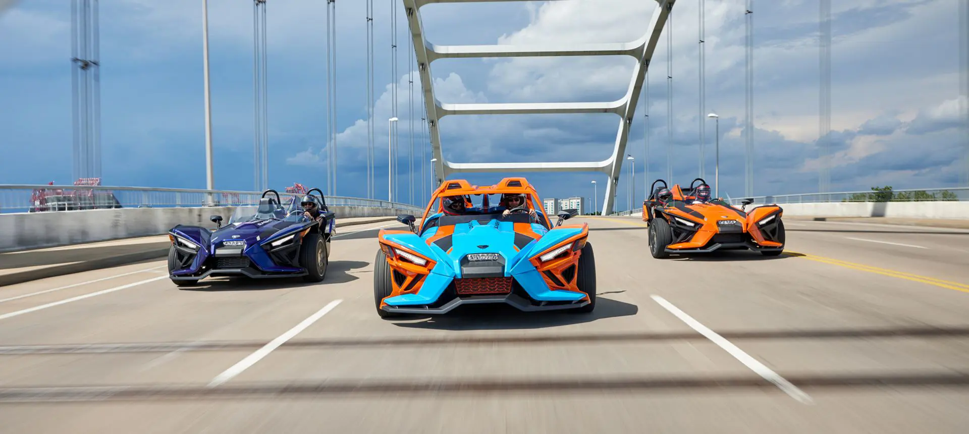 three polaris slingshot SL three-wheeled motorcycles driving on a bridge