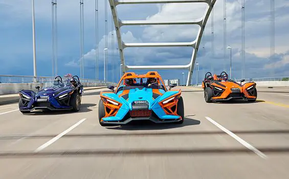 three polaris slingshot SL three-wheeled motorcycles driving on a bridge