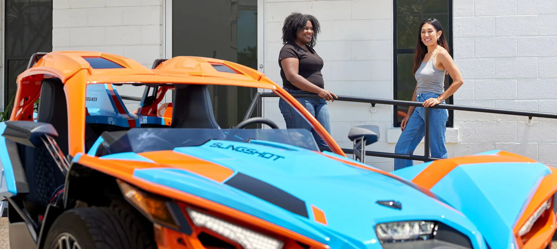 two friends standing near their polaris slingshot sl three-wheeled motorcycle