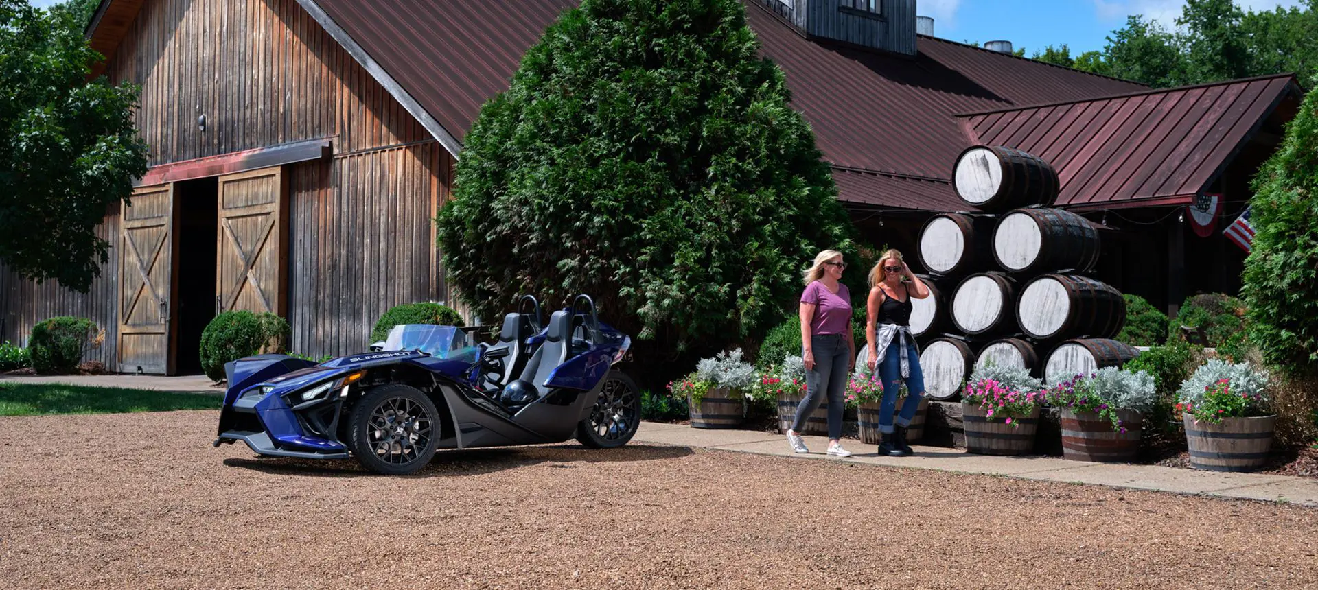 two friends walking away from their polaris slingshot sl three-wheeled motorcycle