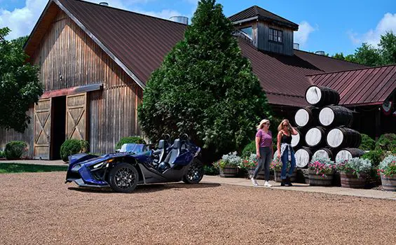 two friends walking away from their polaris slingshot sl three-wheeled motorcycle