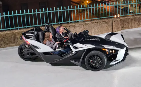 2 women laughing in a 2024 polaris slingshot slr three-wheeled motorcycle