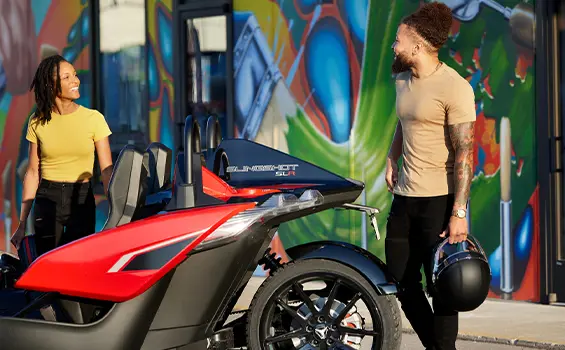 people walking towards a 2024 polaris slingshot slr three-wheeled motorcycle