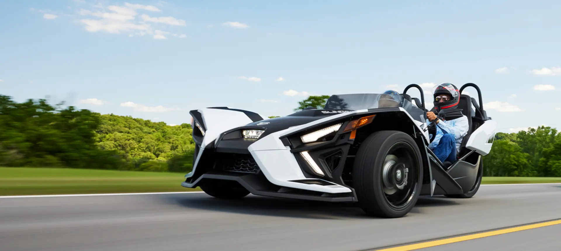 profil latéral d’une moto à trois roues polaris Slingshot slr 2024 en train de rouler sur une route