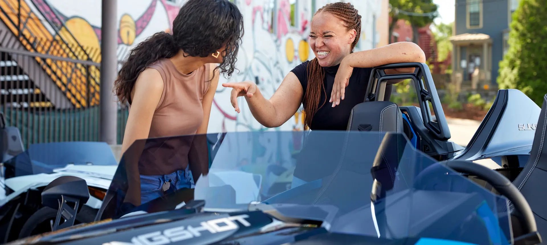 2 femmes riant près d’une moto à trois roues polaris slingshot slr 2024