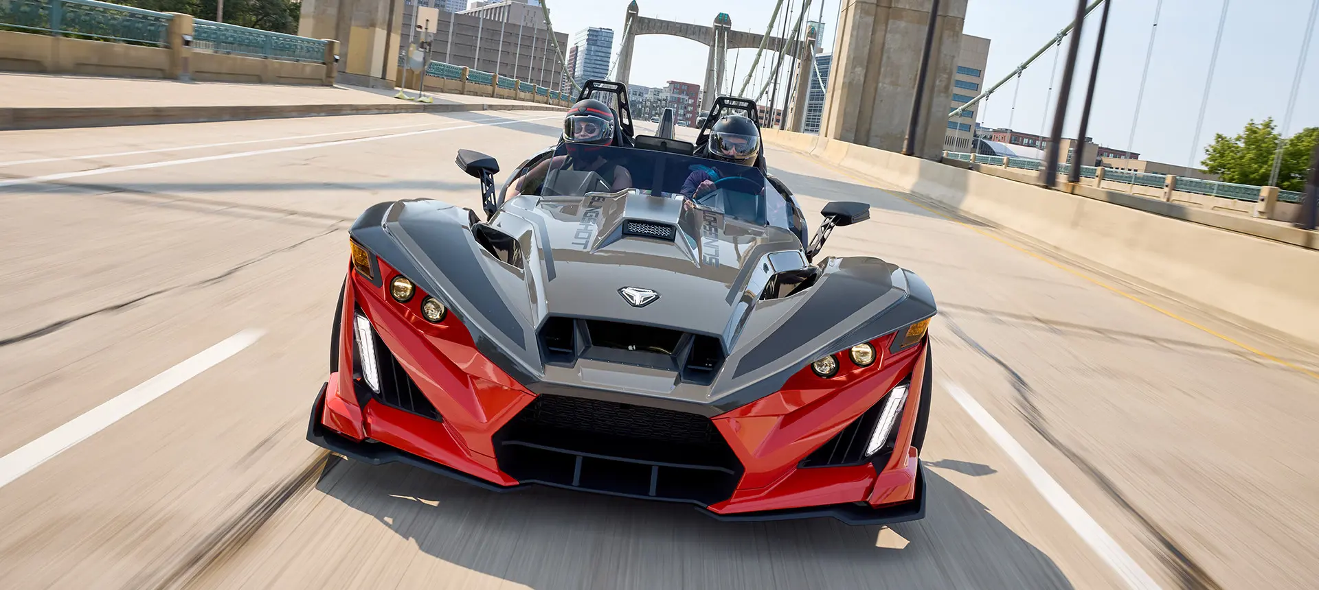 Vue frontale d’un cabriolet à 3 roues Polaris Slingshot R 2025 circulant dans la rue d’une ville.