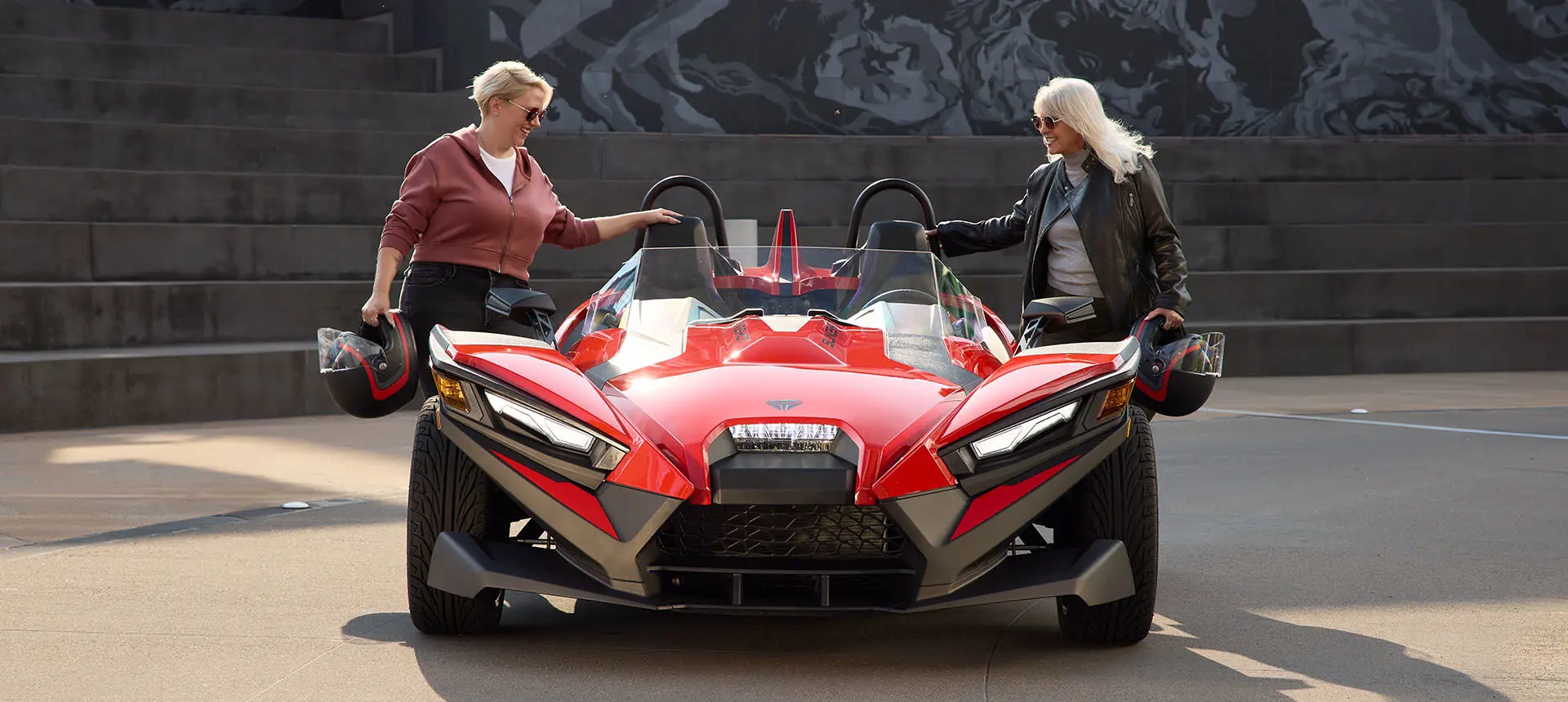 2 women with helmets stepping into a 2026 Polaris Slingshot S.