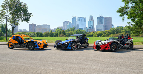 Tres vehículos de tres ruedas Polaris Slingshot, personalizados con diferentes accesorios. 