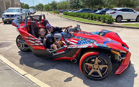 Woman Slingshot rider Danna F. smiles with daughter in a Polaris Slingshot vehicle.