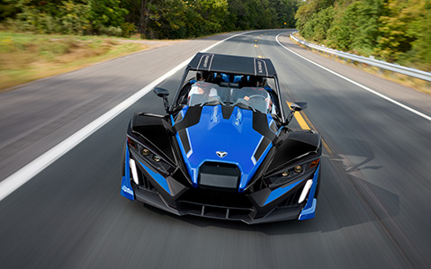 Deux personnes roulant sur une route dans un Polaris Slingshot équipé d’accessoires personnalisés.