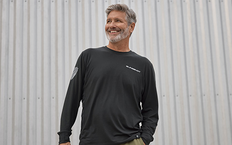 A smiling man wearing a black Polaris Slingshot long-sleeved shirt.