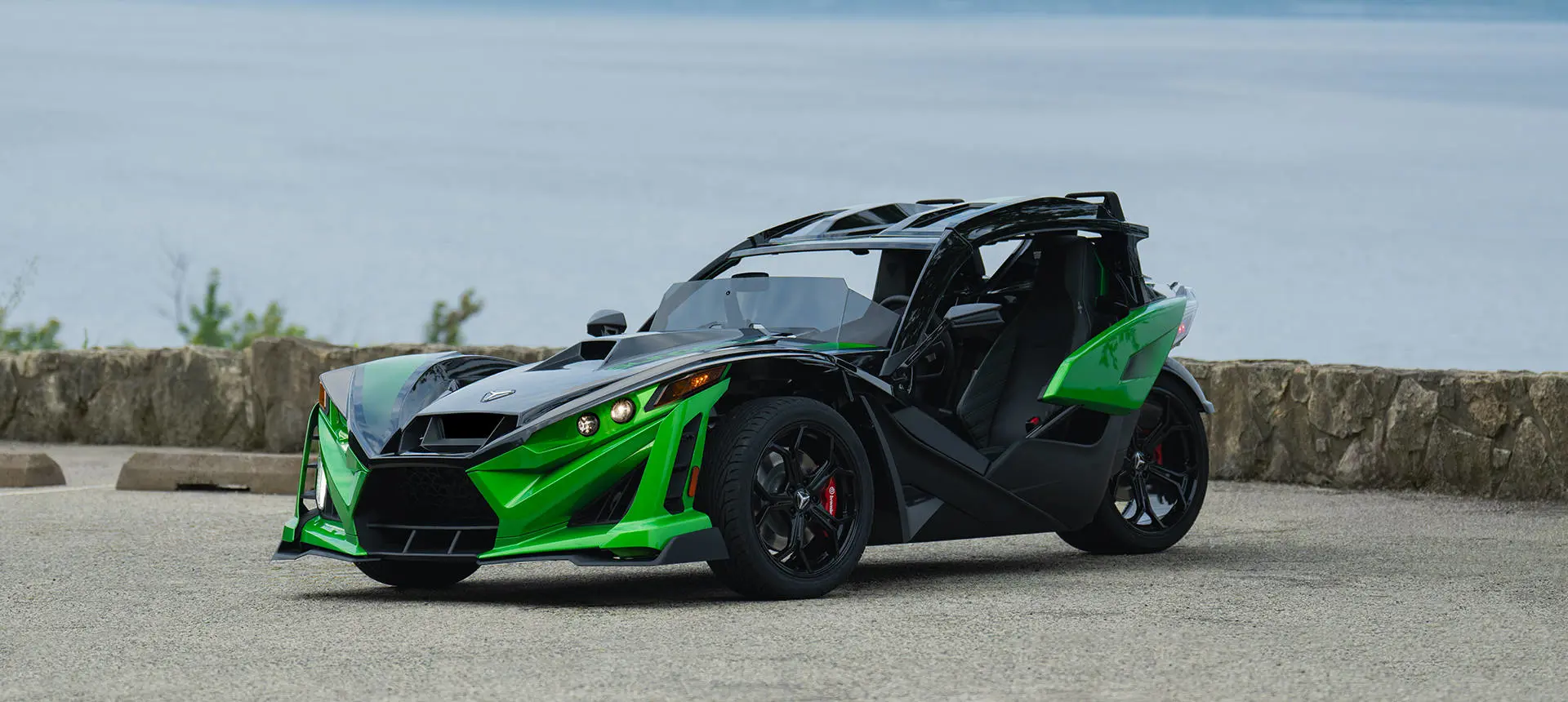Side profile of a 2026 Polaris Slingshot Grand Touring limited edition three-wheeled roadster cruising down the road.