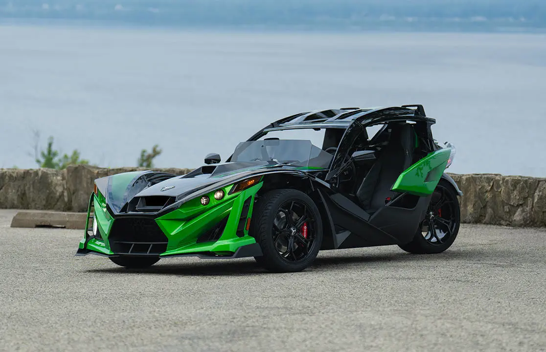 Side profile of a 2026 Polaris Slingshot Grand Touring limited edition three-wheeled roadster cruising down the road.