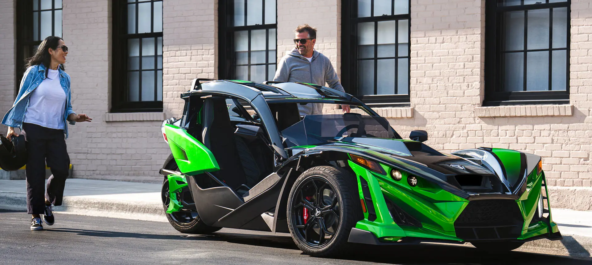 2 people preparing to ride a 2026 Polaris Slingshot Grand Touring limited edition three-wheeled roadster.