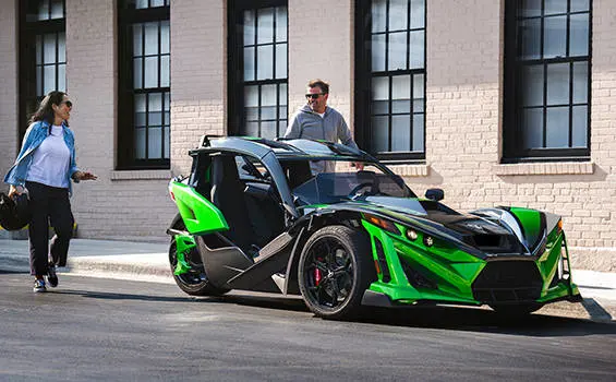 2 people preparing to ride a 2026 Polaris Slingshot Grand Touring limited edition three-wheeled roadster.