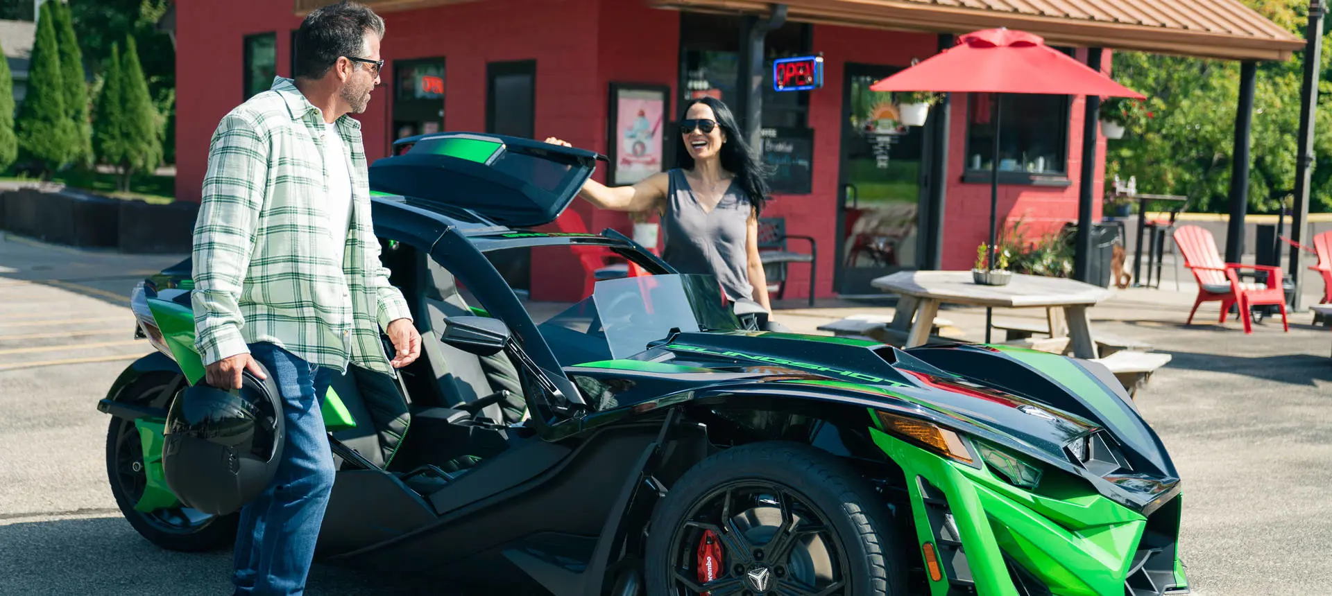 2 people preparing to ride a 2026 Polaris Slingshot Grand Touring limited edition three-wheeled roadster.