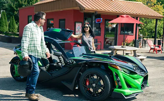 2 people preparing to ride a 2026 Polaris Slingshot Grand Touring limited edition three-wheeled roadster.