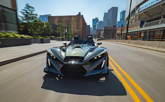 Front end view of a 2026 Polaris Slingshot Signature Edition 3-wheeled roadster cruising down a city street.