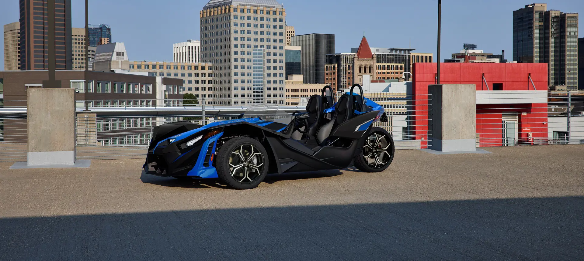 Side profile of a 2026 Polaris Slingshot SLR three-wheel roadster parked in a city.