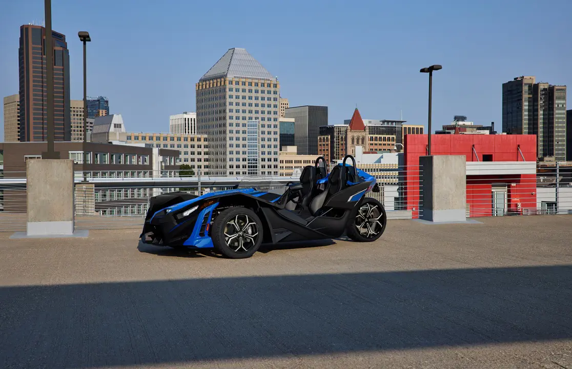 Side profile of a 2026 Polaris Slingshot SLR three-wheel roadster parked in a city.