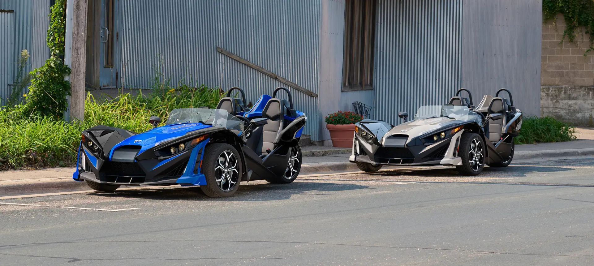 2 2026 Polaris Slingshot SLR three-wheel roadsters parked on a city street.