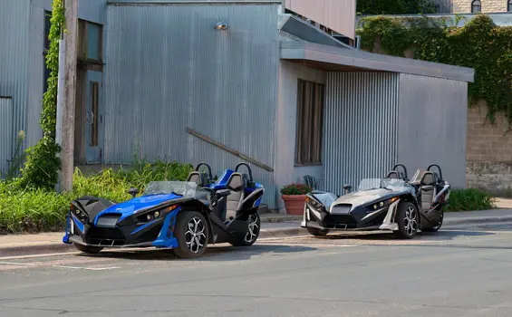 2 2026 Polaris Slingshot SLR three-wheel roadsters parked on a city street.