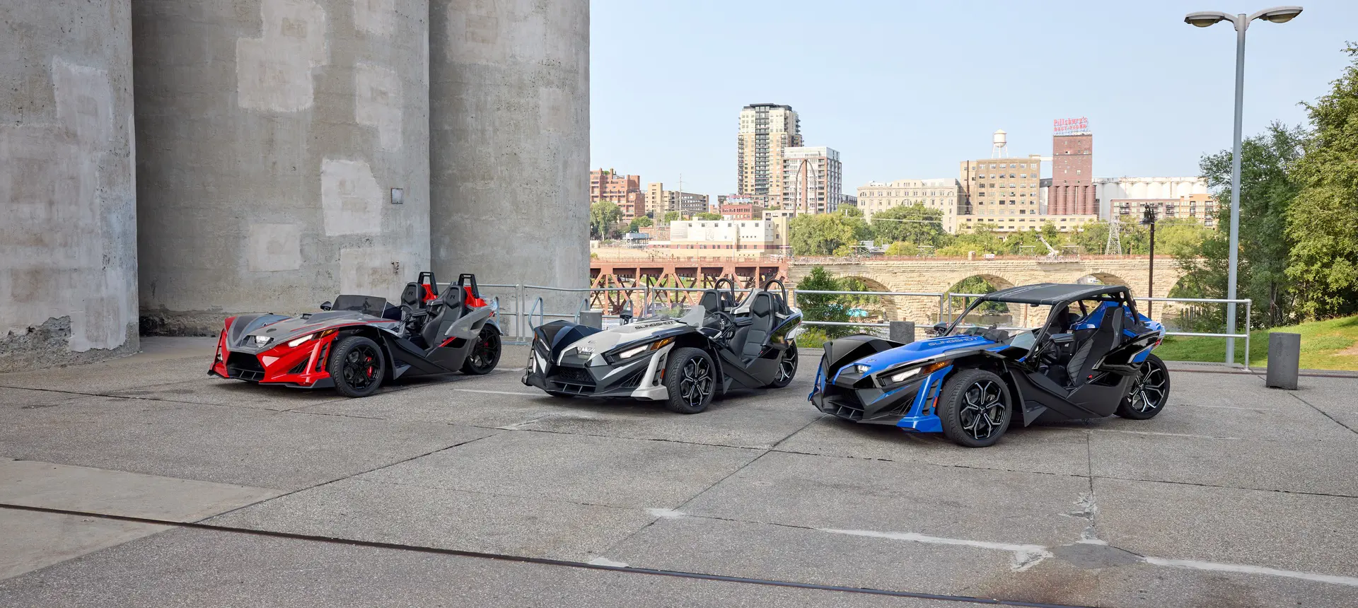 Three 2026 Polaris Slingshot SLR three-wheel motorcycles of varying colors parked in a lineup.