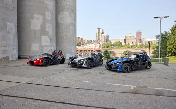 Three 2026 Polaris Slingshot SLR three-wheel motorcycles of varying colors parked in a lineup.