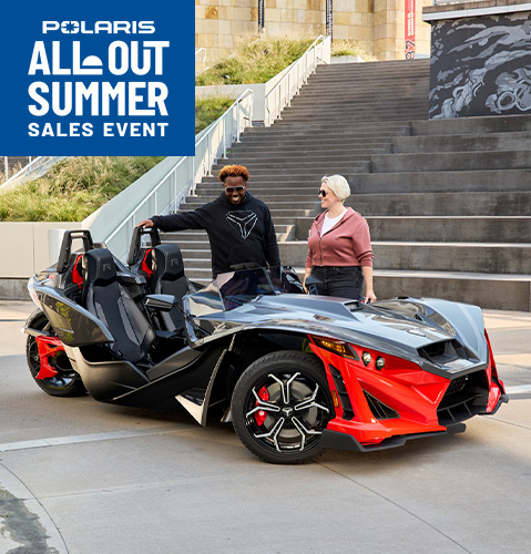 Three Polaris Slingshot vehicles parked with downtown skyscrapers in the distance.