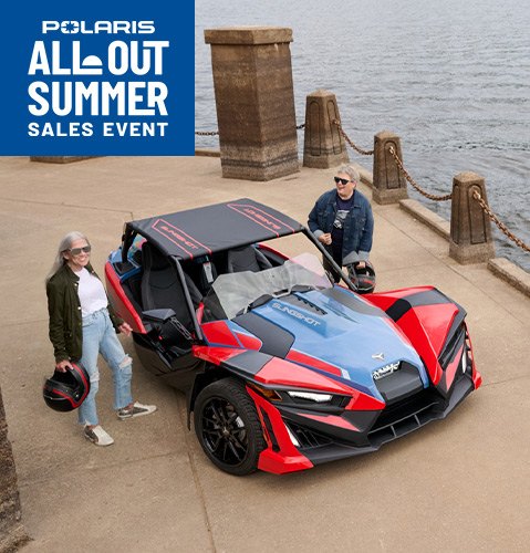 Three parked Polaris Slingshot vehicles in front of brick building.