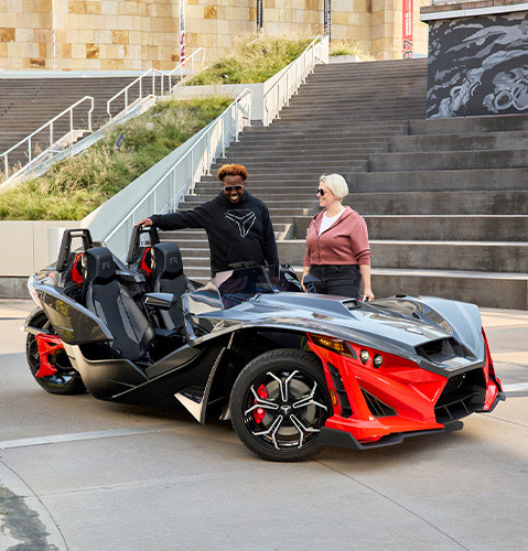 Three Polaris Slingshot vehicles parked with downtown skyscrapers in the distance.