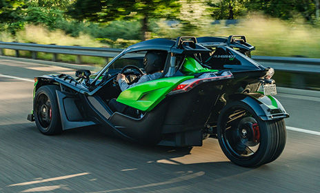 Polaris Slingshot three wheel motorcycle with a color-matched Slingshade & rear fender driving across a bridge on a sunny day, capturing open-road freedom and performance.
