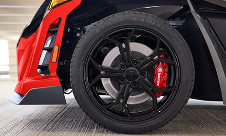 Close-up of Polaris Slingshot front wheel with Brembo brakes and bold red and black detailing.


