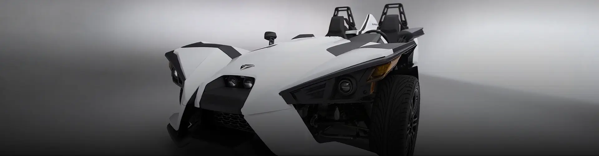 White Polaris Slingshot autocycle shown from the front against a dark studio background.
