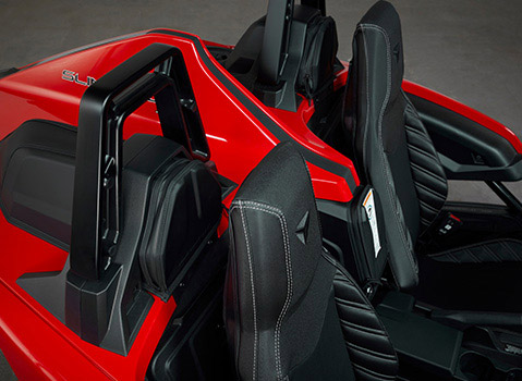 Close-up of black quilted seats and rear storage bags inside a red Polaris Slingshot three-wheel vehicle.