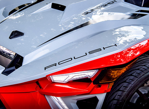 Close-up of the red and white front bodywork, LED headlight and front wheel on a Polaris Slingshot Roush Edition.