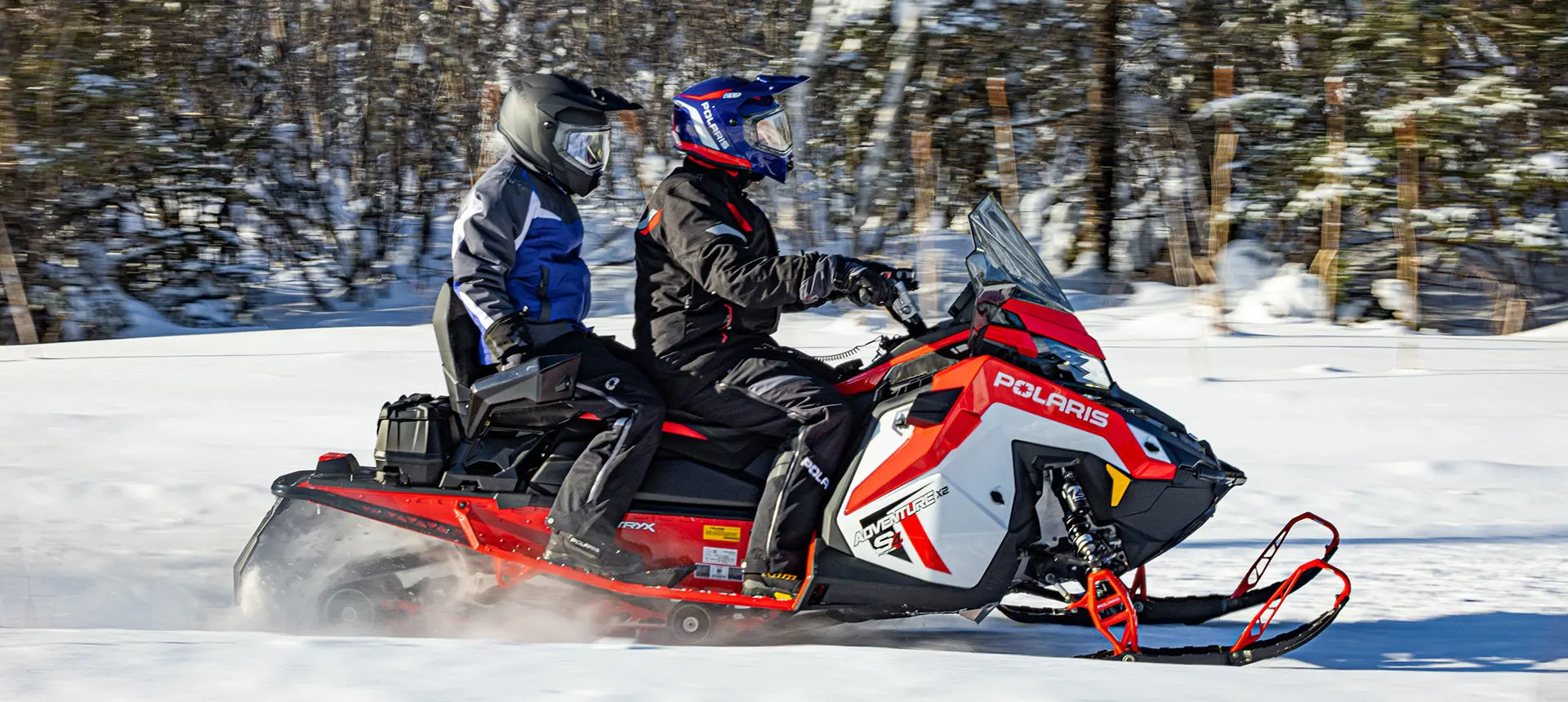 side view of 2 riders on a polaris adventure x2 snowmobile